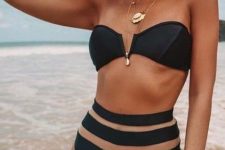 34 a catchy black bikini with a deep cut bandeau top and a catchy striped high waist bottom, layered necklaces and a hat