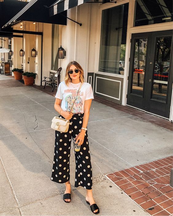 a casual summer look with a printed t shirt, black polka dot pants, black slippers, a pink bag