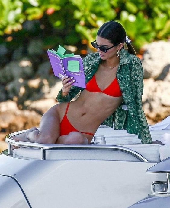 Kendall Jenner wearing a neon red bikini with a bra and a classic bottom plus a green printed cover up looks fabulous