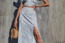 With beige wide brim hat, light blue and white floral printed midi skirt, sunglasses, beige straw rounded bag and white leather mules
