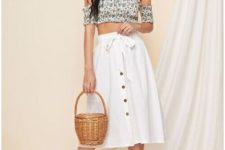 With green and white floral off the shoulder crop top, silver earrings, straw basket and beige and transparent heeled mules