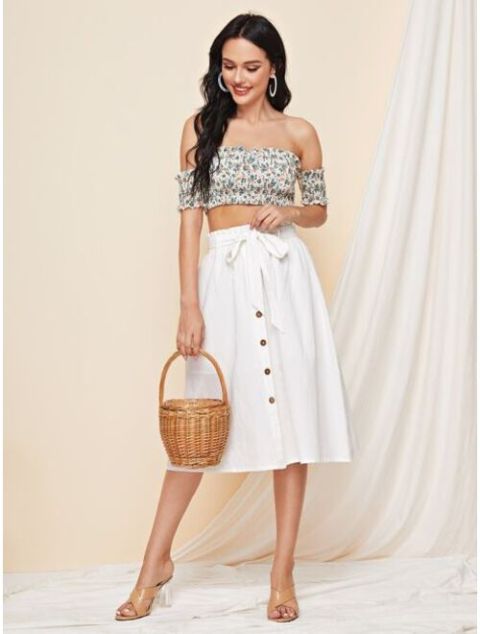 With green and white floral off the shoulder crop top, silver earrings, straw basket and beige and transparent heeled mules