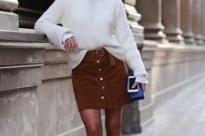 With rounded sunglasses, white button down shirt, white loose sweater, blue leather clutch and brown velvet mid calf boots