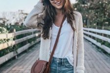 With rounded sunglasses, white loose t-shirt, distressed denim shorts and brown leather crossbody mini bag