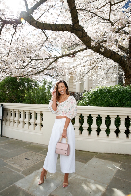 With white high-waisted culottes, pale pink leather bag, beige ankle strap high heels and golden necklace