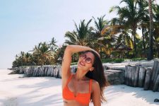 a beautiful neon orange bikini with a cutout bra top and retro-inspired sunglasses are a great combo for a vacation