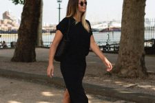 a black midi dress with a high neckline and short sleeves, a back slit, neutral birkenstocks and a black tote