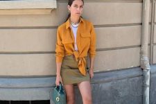 a bold look with a white top, a mellow yellow knotted shirt, green mini, red slides and an emerald mini bag
