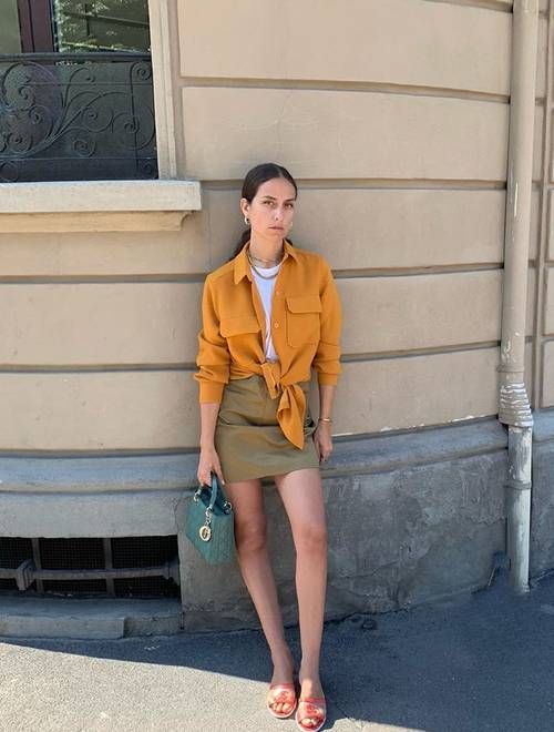 a bold look with a white top, a mellow yellow knotted shirt, green mini, red slides and an emerald mini bag