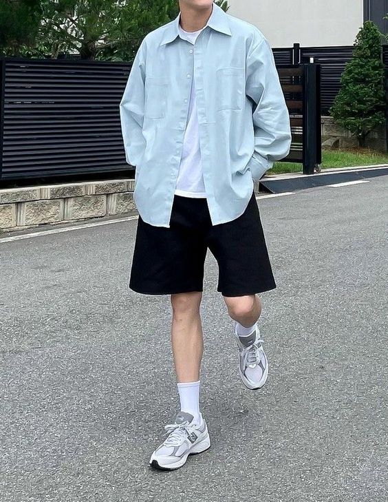 a casual summer outfit with a white tee, a blue oversized shirt, black shorts, white socks and grey trainers