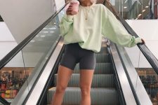 a comfy workout look with a light green oversized sweatshirt, grey biker shorts, white socks and trainers