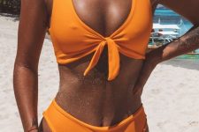 a gorgeous neon orange bikini with a knotted top and a high bottom plus layered seashell necklaces are amazing for standing out