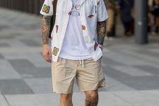 a layered look with a white printed t-shirt, a white printed shirt, tan shorts, white sneakers and a black bag is great for summer