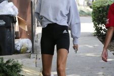 a monochromatic workout look with a grey sweatshirt, black biker shorts, black and white trainers is a cool idea