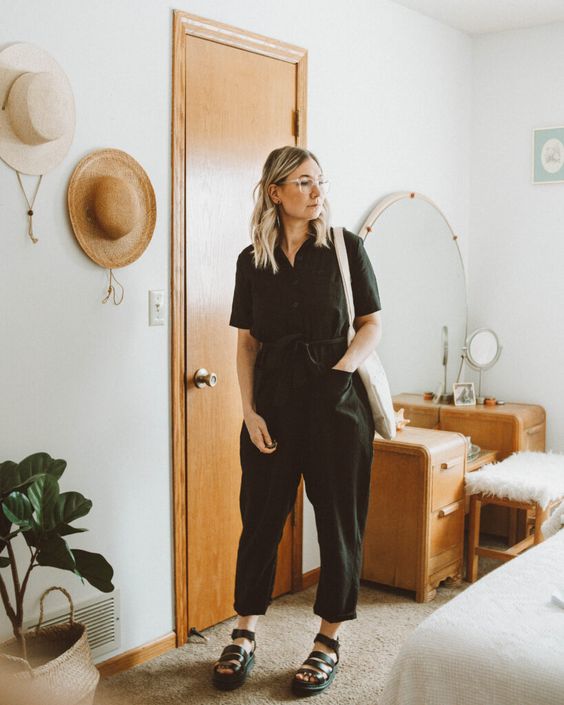 a relaxed summer look with a black linen jumpsuit with short sleeves, strappy sandals and a neutral canvas tote for every day