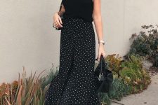 a romantic summer outfit with a black sleeveless top, black polka dot maxi skirt, black slides and a small bag
