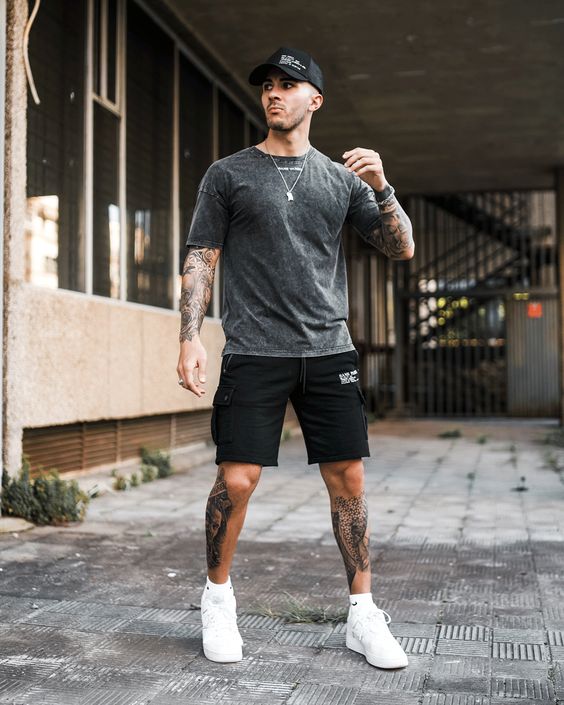 a sport chic outfit with a grey t-shirt, black cargo shorts, white sneakers and socks and a black baseball cap