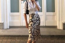 a white knotted button down, a black floral clip midi skirt, black slides and a small black bag for a summer date outfit