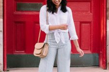 a white linen knotted shirt, vertical striped pants, beige mules and a tan bag plus burgundy sunglasses