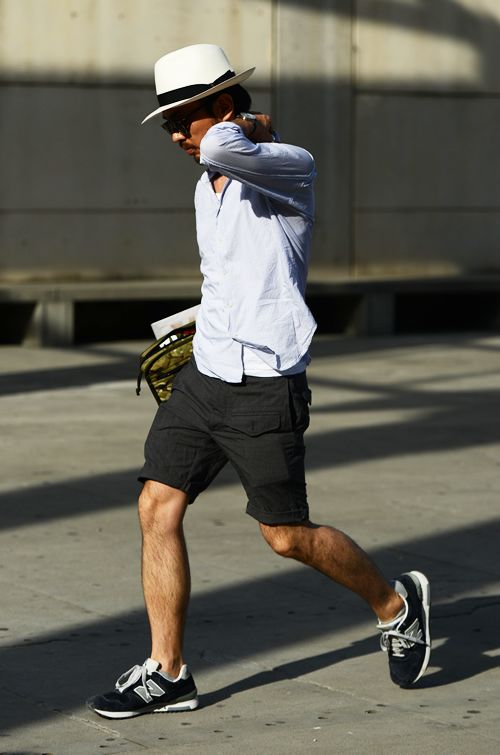 a white tank top, a blue shirt, black cargo shorts, black trainers and a neutral hat are a great combo for summer