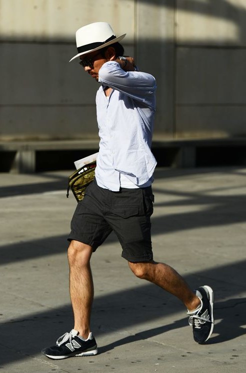 a white tank top, a blue shirt, black cargo shorts, black trainers and a neutral hat for a casual summer date