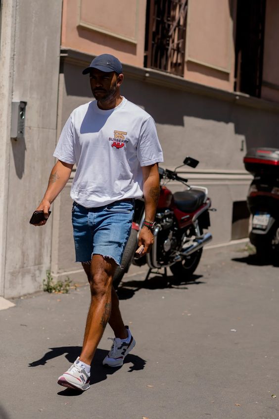 an easy every day summer look with a white printed t shirt, blue denim shorts, white trainers and a navy baseball cap