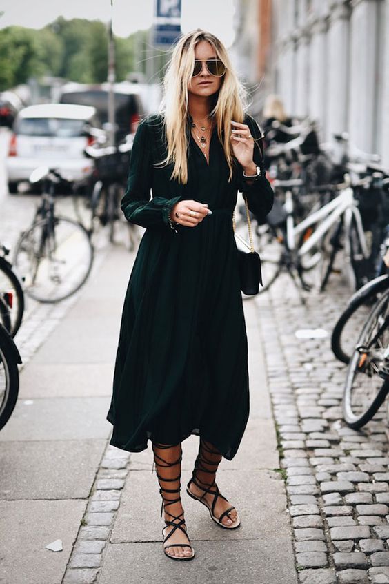 a black A-line midi shirtdress with long sleeves and a V-neckline, black lace up sandals and a black bag