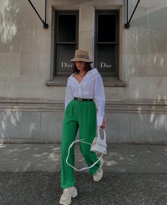 a bold and comfortable outfit with an oversized white shirt, green high waisted pants, neutral trainers, a white bag and a bucket hat