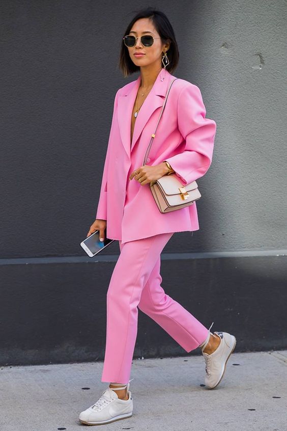 a bold pink pantsuit with an oversized blazer, neutral sneakers and a neutral bag are a lovely summer work look