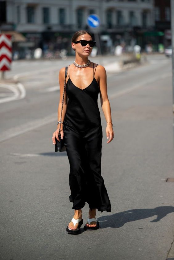 a black slip maxi dress, a statement necklace, neutral flipflops and a black bag is a stylish look for summer