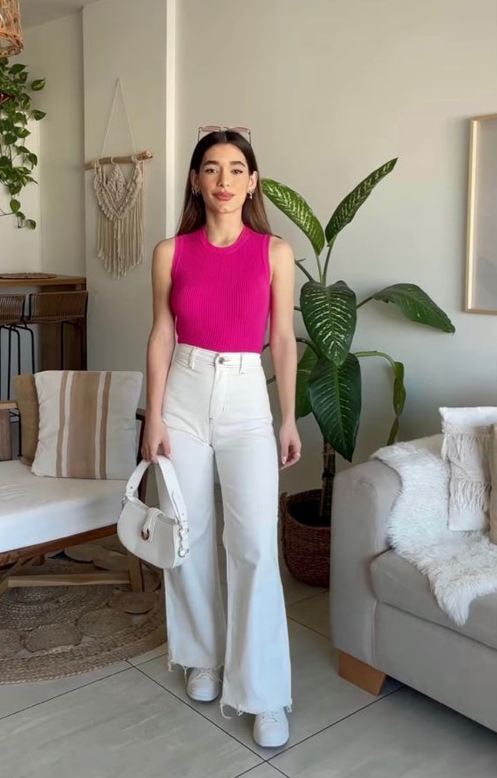 a simple summer work look with a fuchsia sleeveless top, white high-waisted flare jeans, white sneakers and a white bag