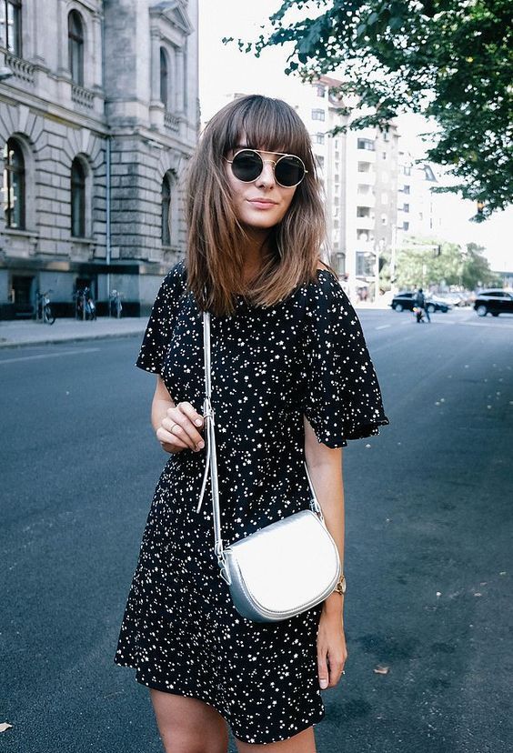 a black floral print over the knee dress with short sleeves and a silver handbag are a cool combo for summer