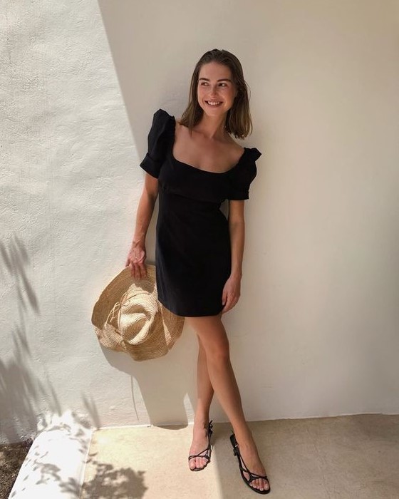 a lovely summer date look with a black mini dress with a square neckline, short sleeves, strappy sandals and a straw hat