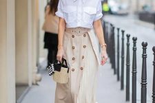 With beige and black wide brim hat, white short sleeved button down shirt, black and beige straw mini bag and black and white polka dot pumps