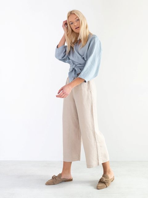 With beige linen culottes and gray suede flat mules