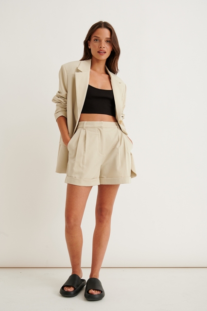 With beige linen shorts and black leather flat sandals