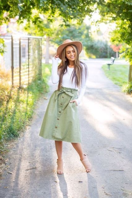 With beige wide brim hat, white long sleeved shirt and beige suede cutout ankle boots