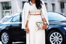 With mirrored sunglasses, white high-waisted midi skirt, white ankle strap shoes and printed chain strap bag