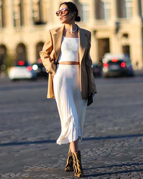 With oversized sunglasses, necklace, white high-waisted pleated midi skirt and printed mid calf boots