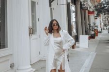 With rounded sunglasses, white long blazer, black bag and white lace up flat shoes