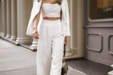 With white and beige striped palazzo pants, embellished sandals and beige bag