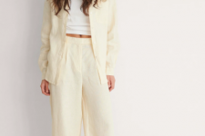 With white crop top, beige long jacket and brown leather flat sandals