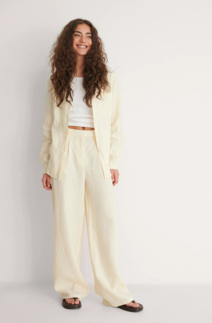 With white crop top, beige long jacket and brown leather flat sandals