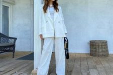With white fitted shirt, white loose blazer, wide brim hat, sunglasses, beige leather sandals, black and beige bag and golden necklace