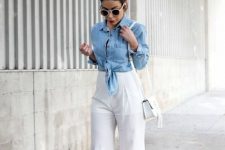 With white framed rounded sunglasses, black top, light blue denim jacket, white leather tassel mini bag and beige shoes