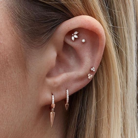 a beautifully curated ear with a faux rook, a flat and two helix piercings plus a double lobe piercing all done with a chic set of earrings