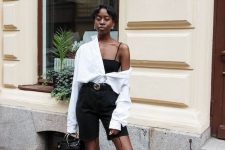 a black and white look with a spaghetti strap top, black biker shorts, black shoes, an oversized white shirt and a black bag