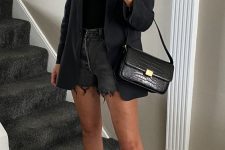 a black summer outfit with a top, denim shorts, a blazer, a black bag and tan strappy shoes