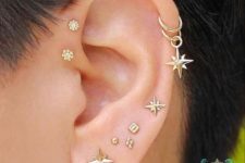 a bold and glam ear set with a double forward helix, double helix and stacked lobe piercings done with gold studs and hoops