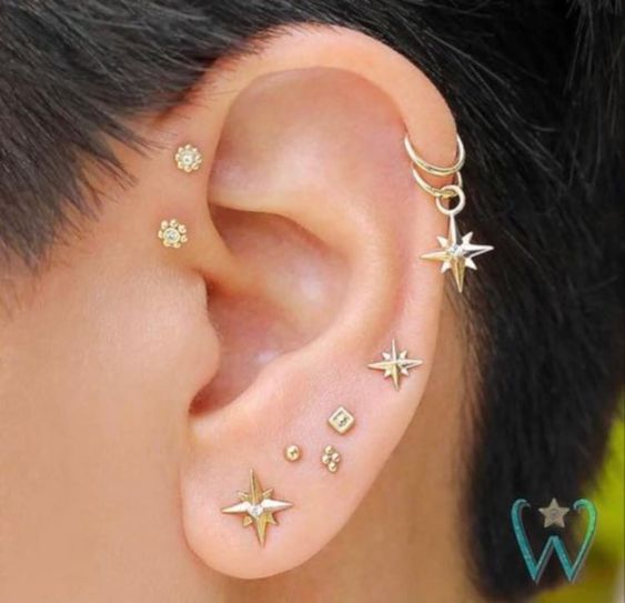 a bold and glam ear set with a double forward helix, double helix and stacked lobe piercings done with gold studs and hoops